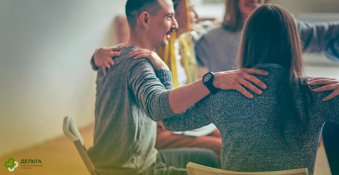 Люди держат друг друга за плечи, сидя в круге